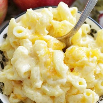close up of macaroni and cheese in a small bowl with apple in the background