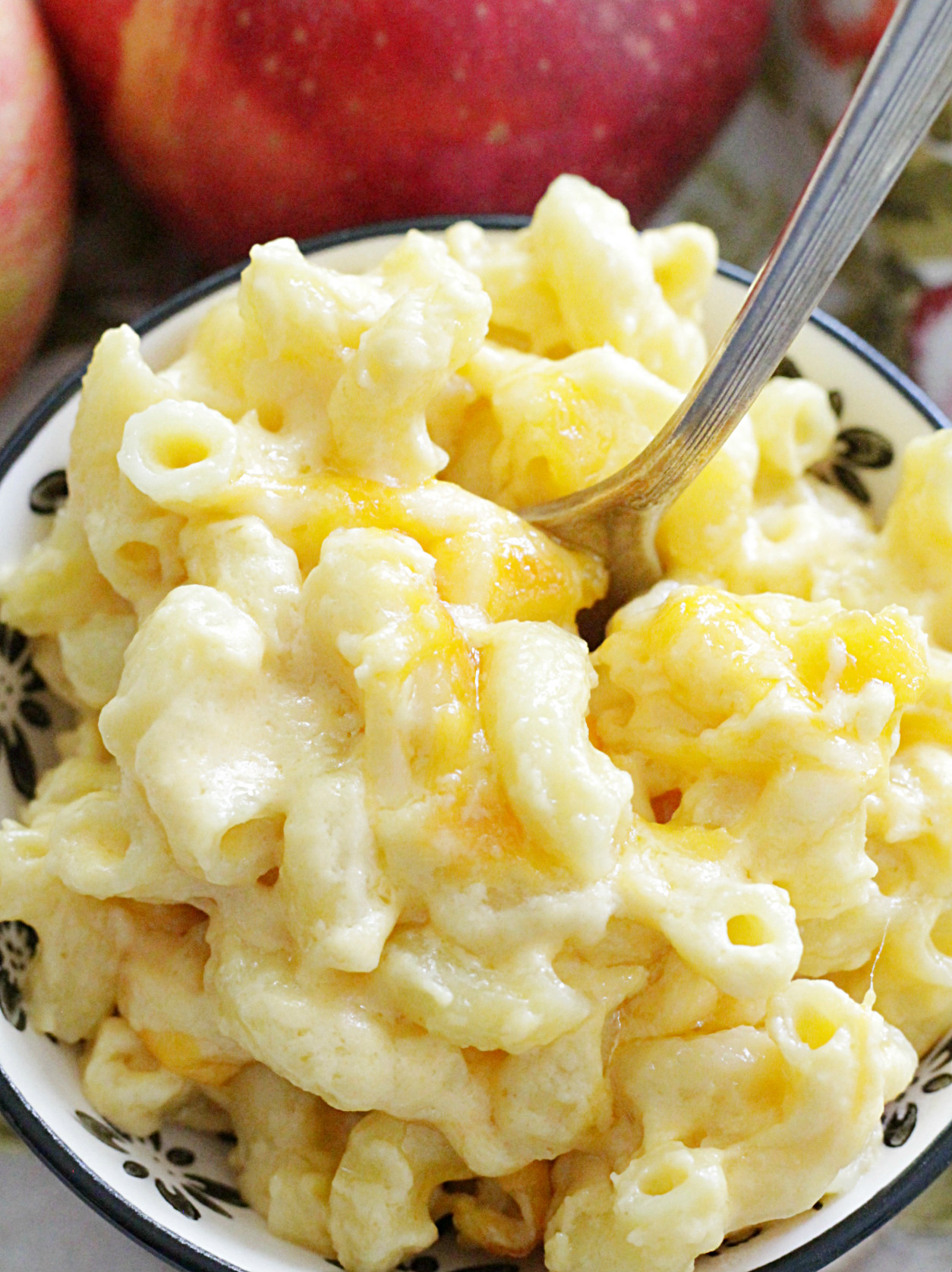 close up of macaroni and cheese in a small bowl with apple in the background