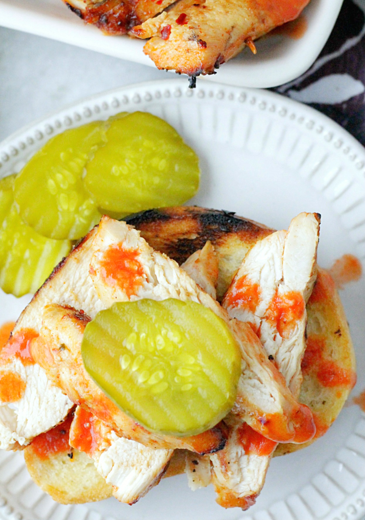 nashville hot grilled chicken on plate with pickles and garlic bread