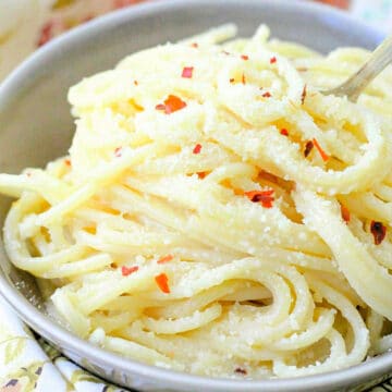 a bowl full of butter spaghetti garnished with red pepper flakes