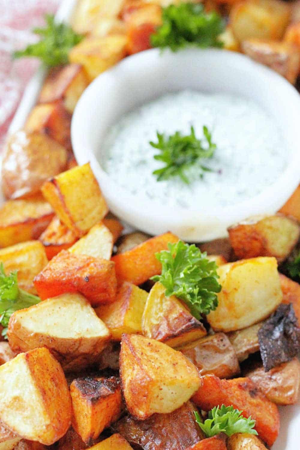 These perfect oven roasted potatoes with creamy herb dipping sauce are a crowd pleasing side dish. They are a mix of sweet potatoes, Yukon Golds and red potatoes. via @foodtasticmom