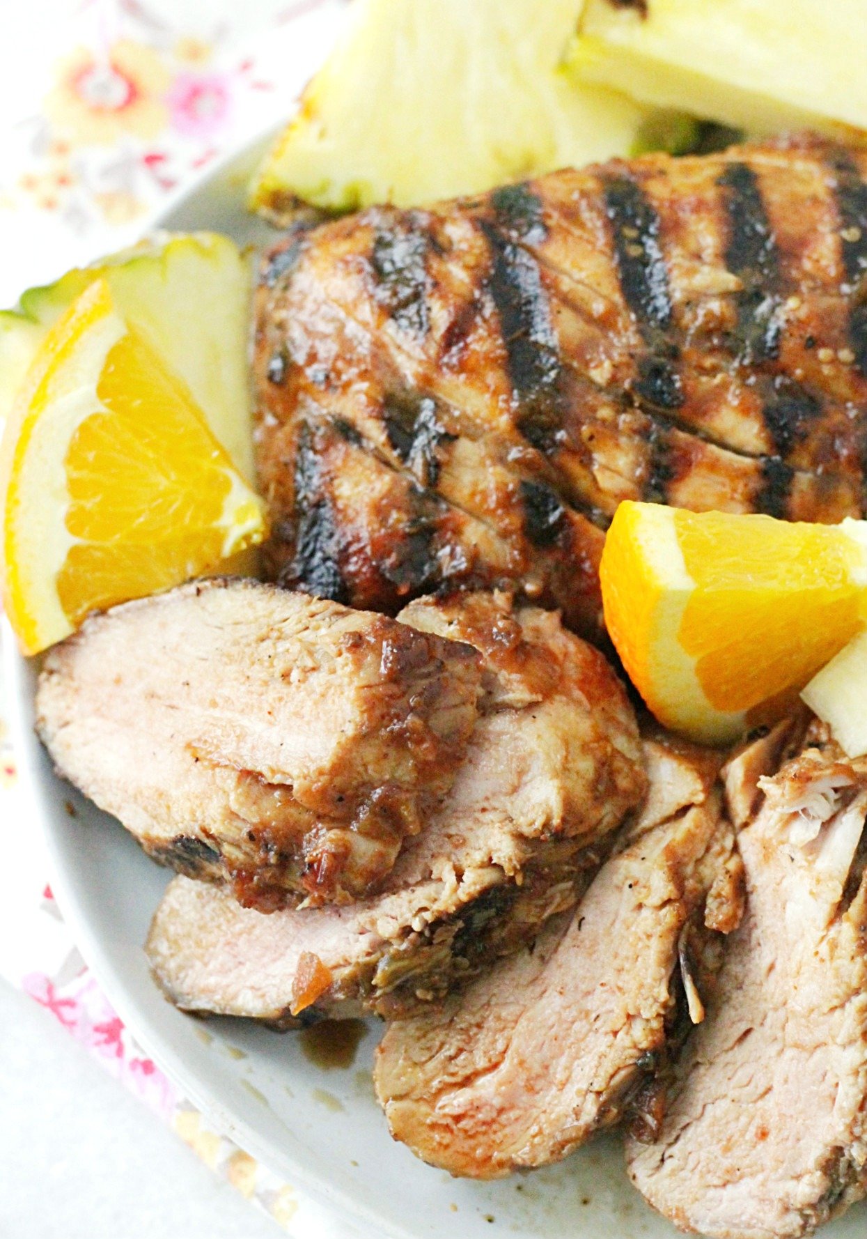 al pastor grilled pork tenderloin sliced on plate with orange slices