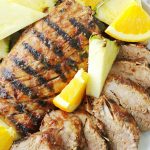 al pastor grilled pork tenderloin on plate with fresh pineapple and orange slices