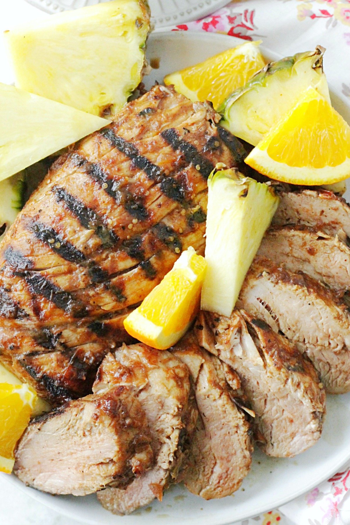 al pastor grilled pork tenderloin on plate with fresh pineapple and orange slices