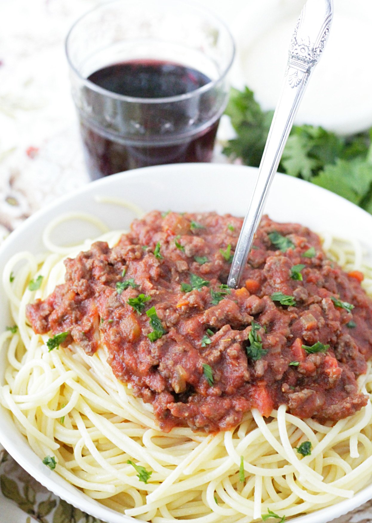 instant pot beef bolognese pasta sauce in a bowl with a glass of red wine on the side