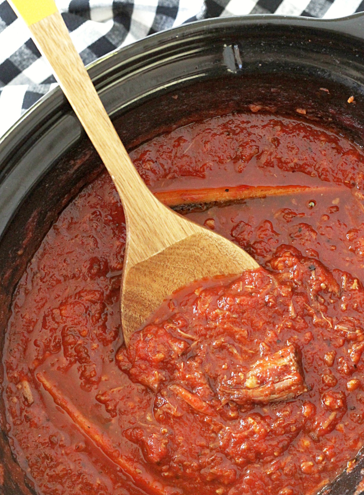 slow cooker short rib sunday gravy in slow cooker with spoon