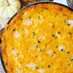pumpkin shepherds pie pictured in a white cast iron skillet with two small pumpkins on the side as decoration