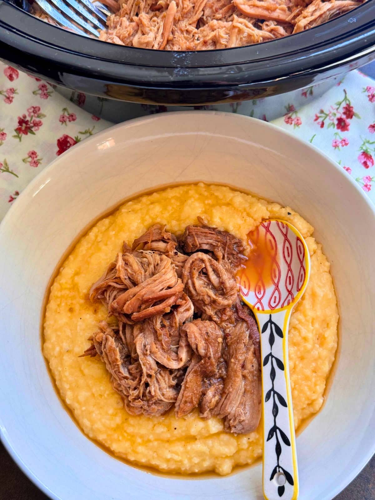 a bowl of apple butter pork and grits setting in front of the crock pot