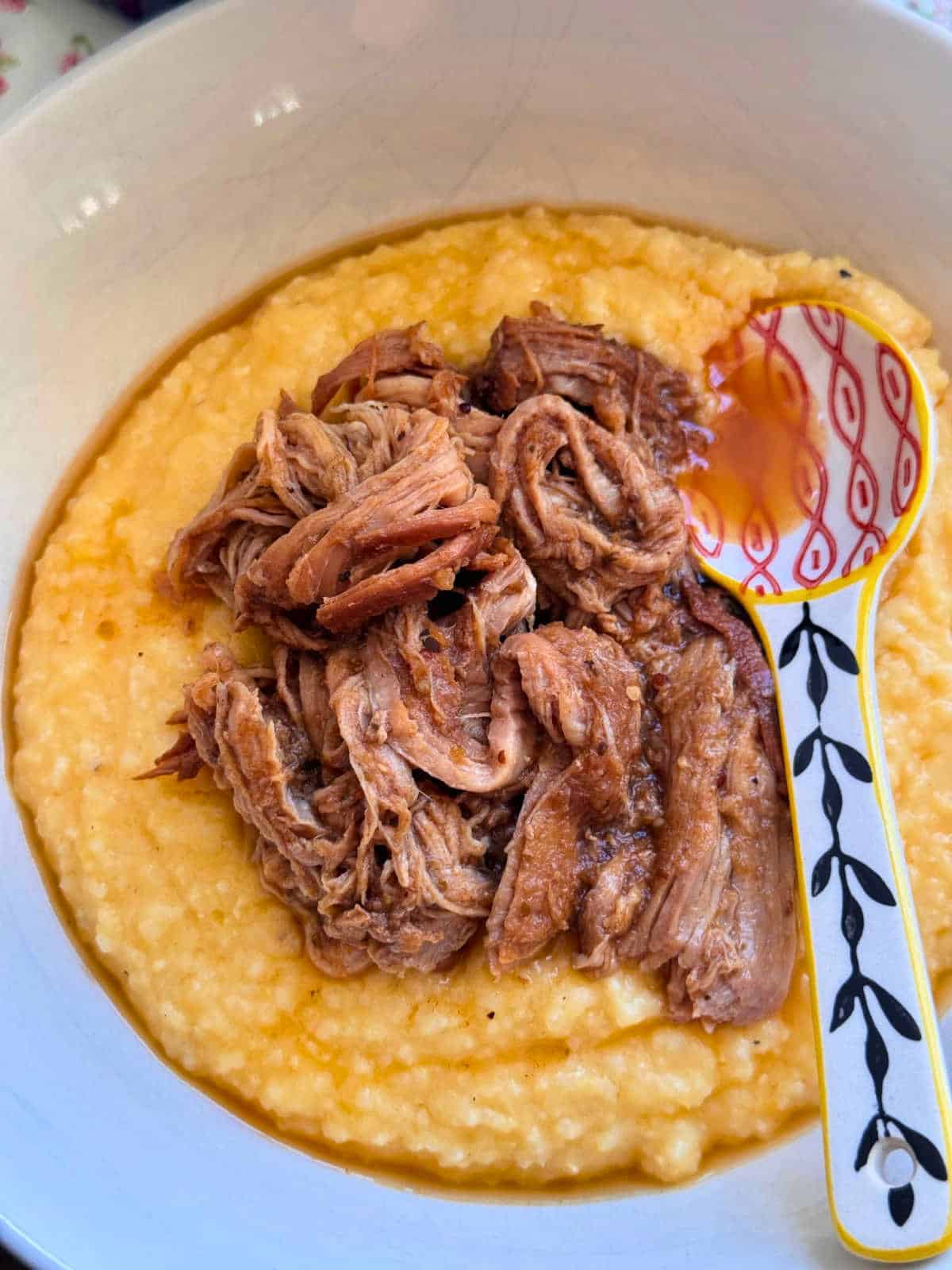 flat lay photo of apple butter pork and grits with a decorate spoon