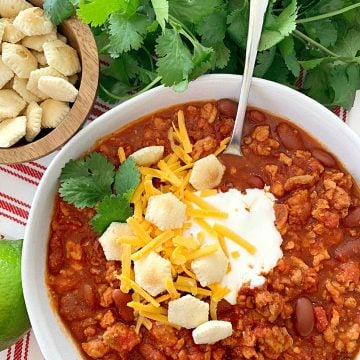 overhead view of turkey chili topped with sour cream, oyster crackers and shredded cheese