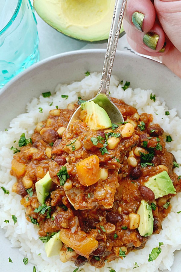 vegetarian chili in bowl with rice and topped with avocado