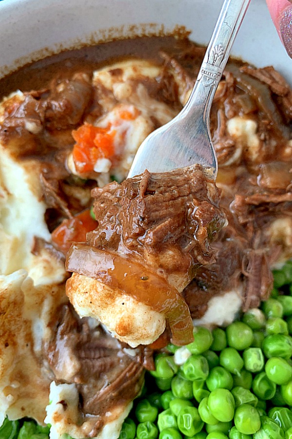 close up of fork with guinness beef stew and mashed potatoes