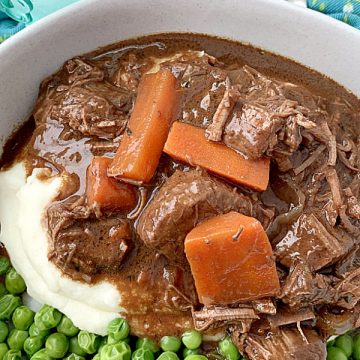 guinness beef stew in bowl with mashed potatoes and peas