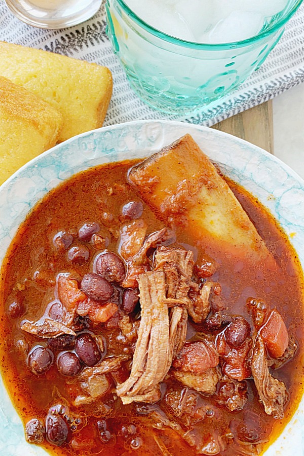 overhead view of slow cooker short rib chili with corn bread on the side