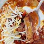 slow cooker short rib chili in bowl topped with cheese and sour cream