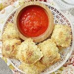 a plate full of air fryer ravioli with a small bowl of marinara sauce for dipping