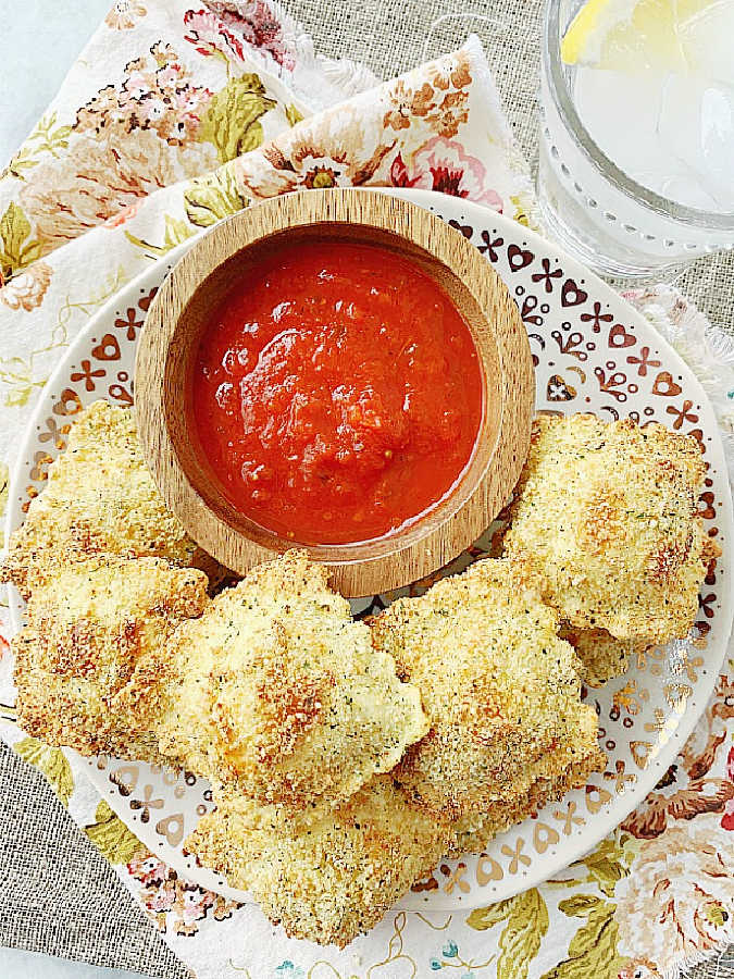 a plate of fried air fryer ravioli with a bowl of marinara sauce for dipping