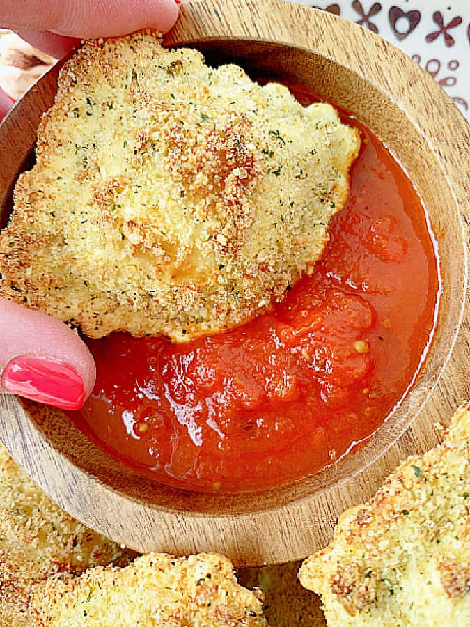 dipping a toasted cheese ravioli into the marinara sauce