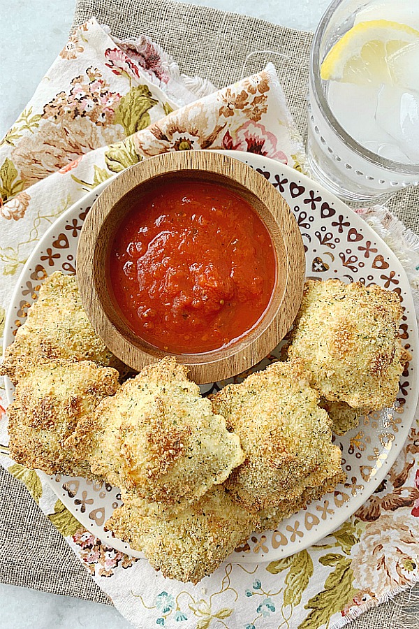 air fryer toasted ravioli on plate with bowl of pizza sauce for dipping