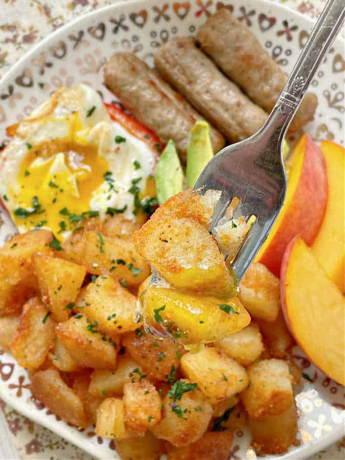 dipping a forkful of the breakfast potatoes into the fried egg