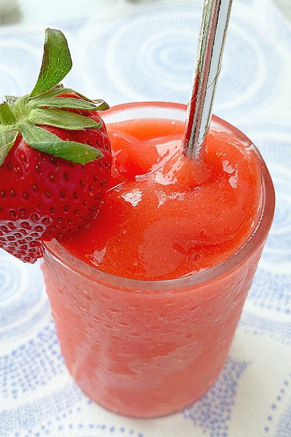 glass of strawberry daiquiri with strawberry garnish and silver straw