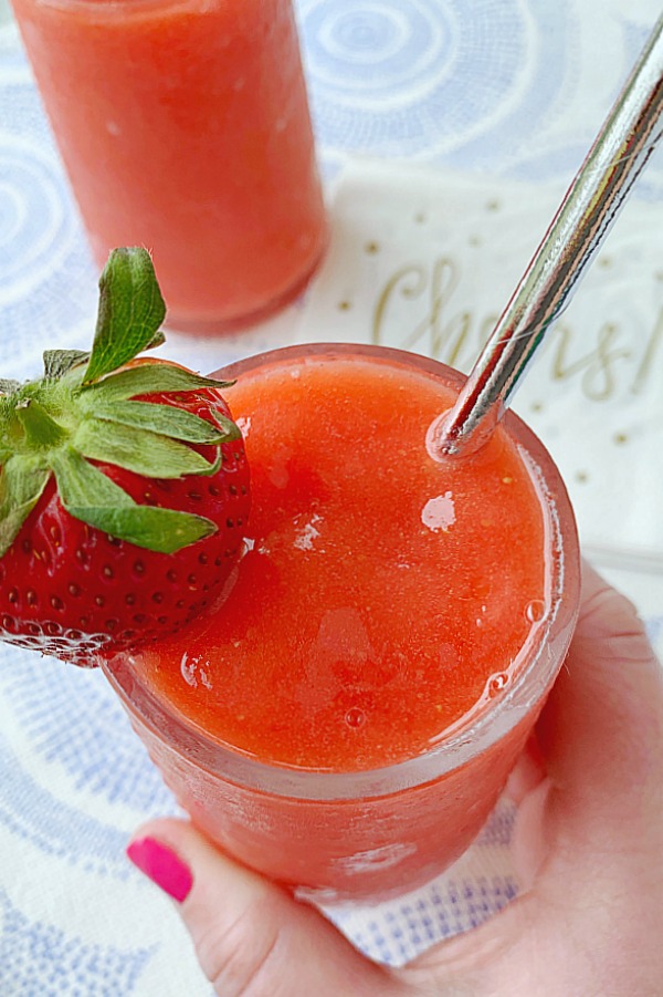 holding a glass of strawberry daiquiri