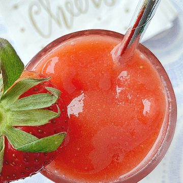 glass of strawberry daiquiri with cheers napkins