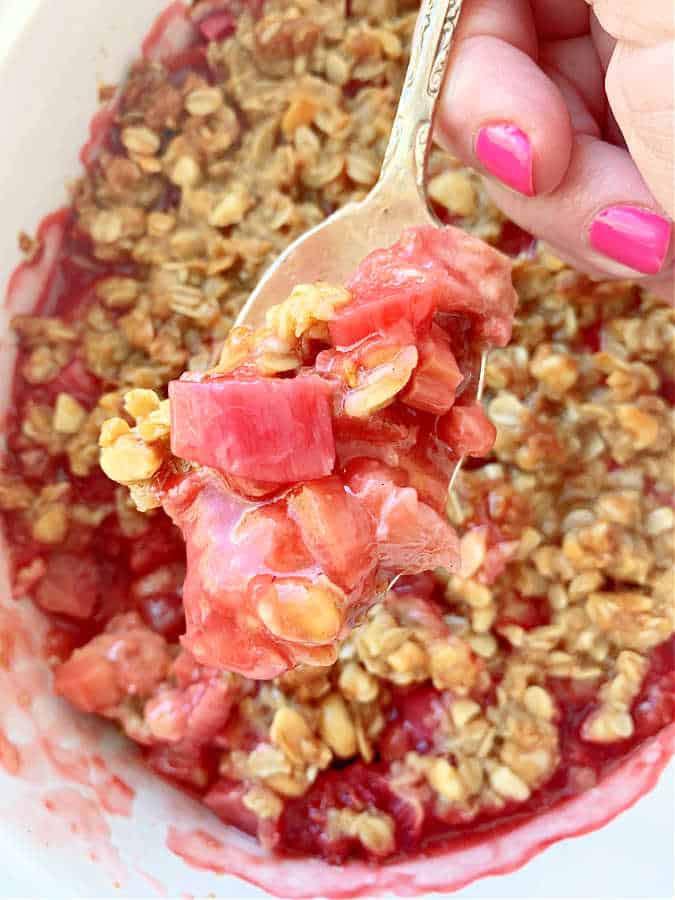 spooning a serving of rhubarb crisp out of its baking dish