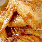 sauce being poured onto air fryer chicken wings