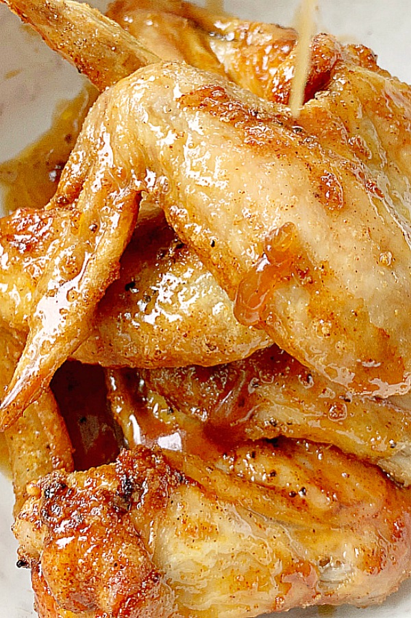 sauce being poured onto air fryer chicken wings