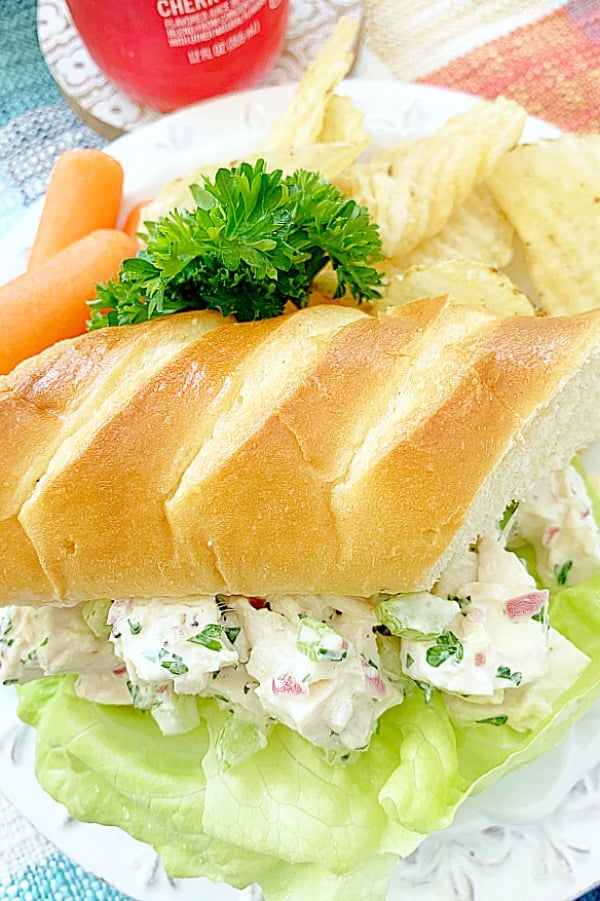 chicken salad sandwich on a plate with chips and carrots