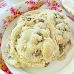 three chocolate and peanut butter chip cookies on a plate with a glass of cold milk on the side