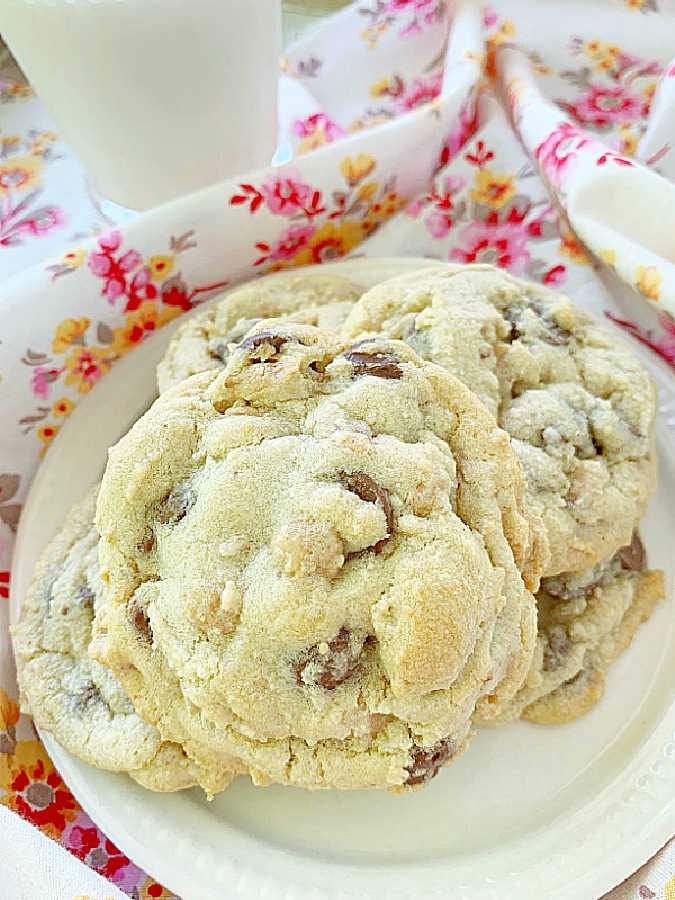 a plate full of cookies with chocolate and peanut butter chips and a glass of milk on the side