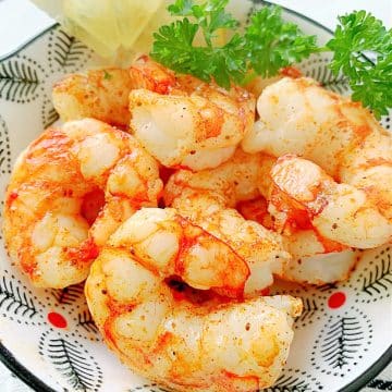 a bowl of just cooked air fryer shrimp, before being drizzled with the buttery lemon garlic sauce