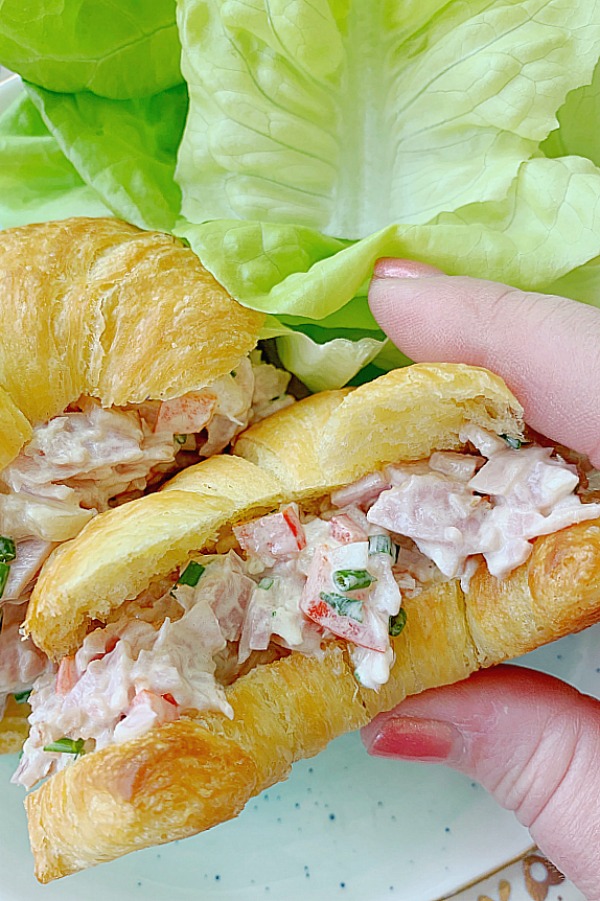 holding ham salad sandwich on croissant