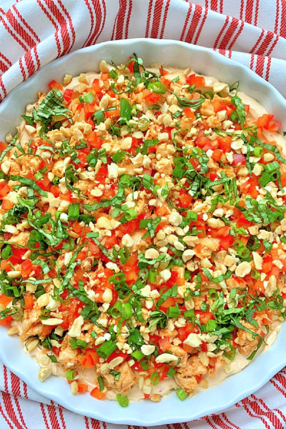 Thai Chili Chicken Dip is a layered dip combining cream cheese, chicken, fresh veggies and chopped peanuts with the sweet and spicy flavors of Thai cuisine. via @foodtasticmom