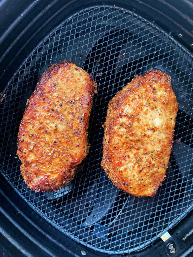 two perfectly browned pork chops in the air fryer basket
