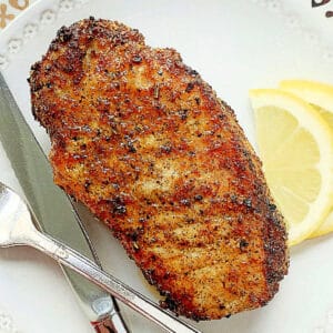 a plated pork chop, fresh out of the air fryer and ready to serve, garnished with lemon slices