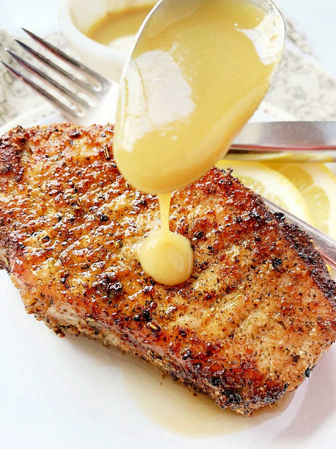 drizzling a seasoned pork chop with maple dijon sauce