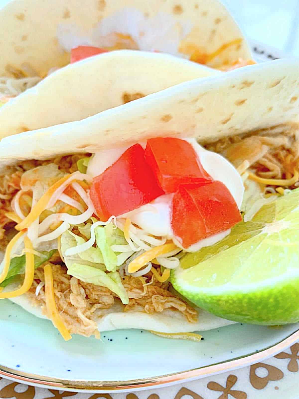 chicken taco on a plate with a lime wedge next to it