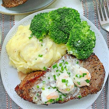 air fryer steak topped with three shrimp and cream sauce plated with mashed potatoes and broccoli