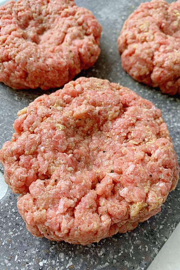 uncooked burgers on cutting board