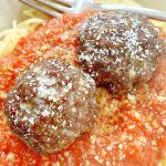 two air fryer meatballs on top of spaghetti and sauce