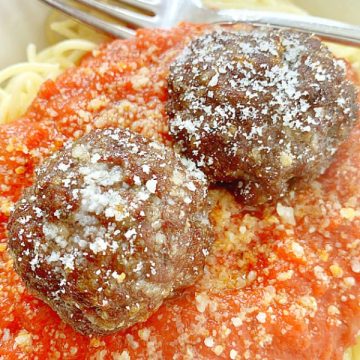 two air fryer meatballs on top of spaghetti and sauce