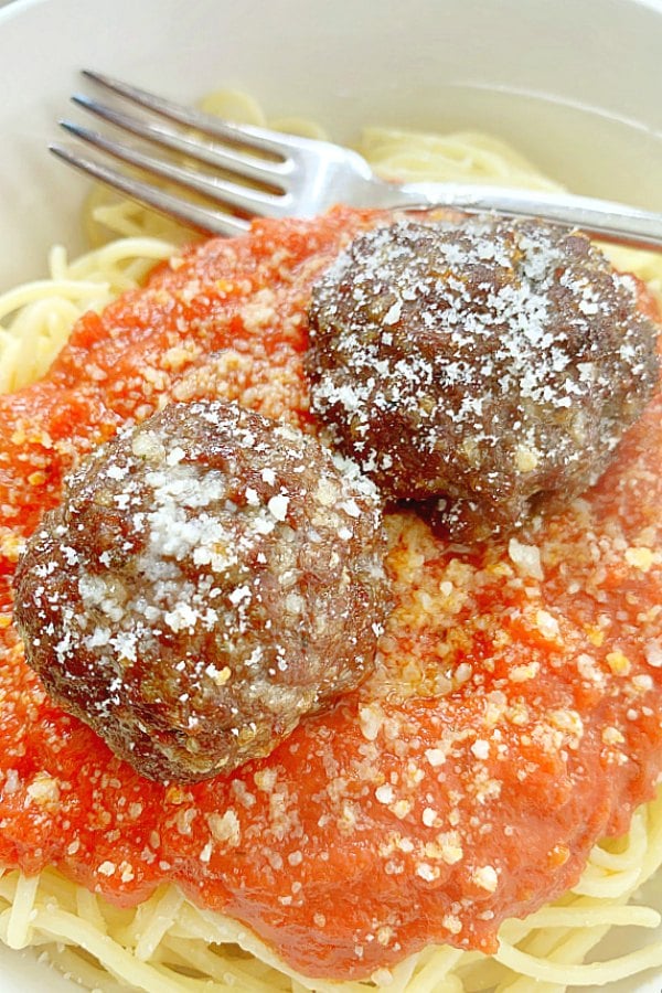 two air fryer meatballs on top of spaghetti and sauce