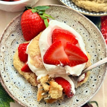 plated strawberry shortcake topped with whipped cream and garnished with a whole fresh strawberry