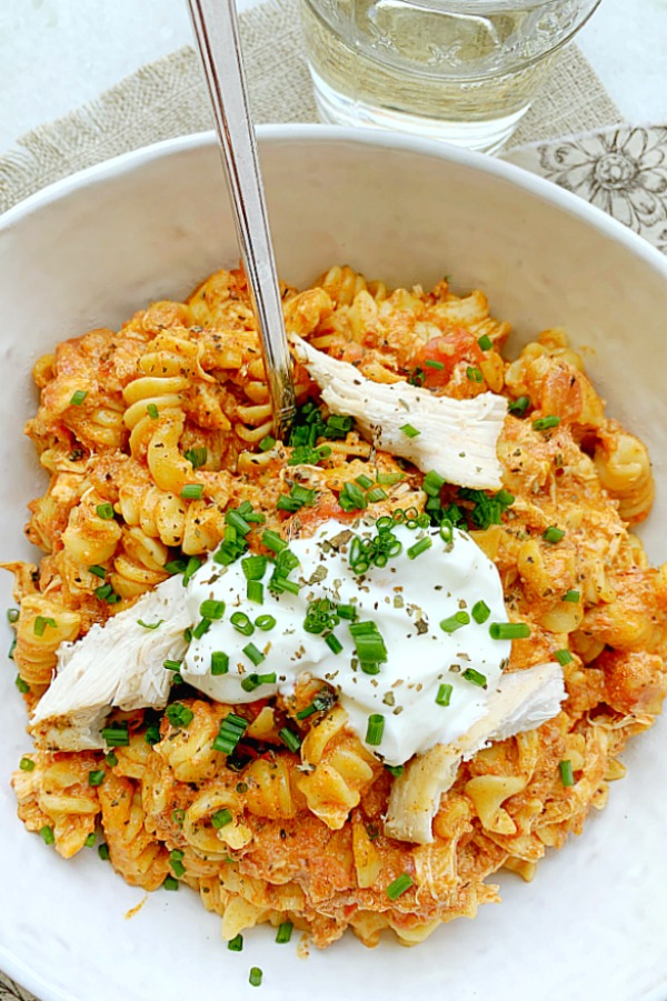 overhead view of chicken and chorizo pasta in bowl with glass of wine