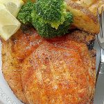 broiled pork chop on a plate with potato wedges