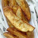 air fryer potato wedges on a platter with lemon wedges