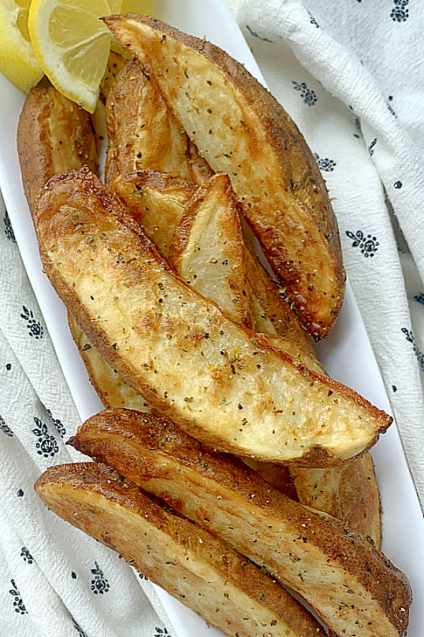 air fryer potato wedges on a platter with lemon wedges